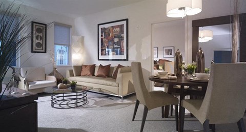 A modern living room with a white couch, a coffee table, and a dining table with chairs.