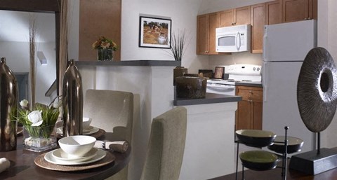 A modern kitchen with a dining table set for two.