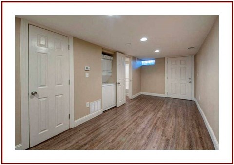a empty living room with white doors and a kitchen