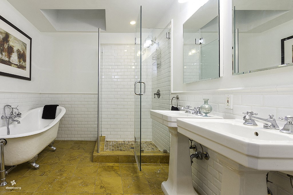 a bathroom with a tub and two sinks and a shower
