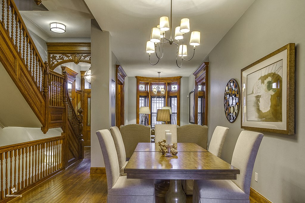 a dining room with a wooden table and chairs and a staircase