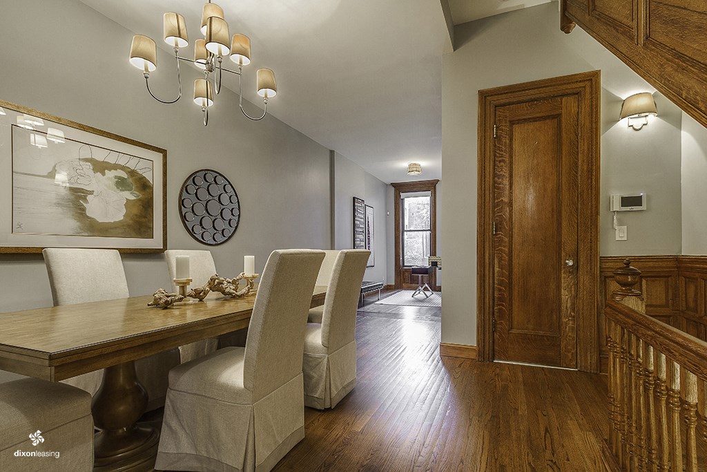 a dining room with a table and chairs and a hallway with a wooden door