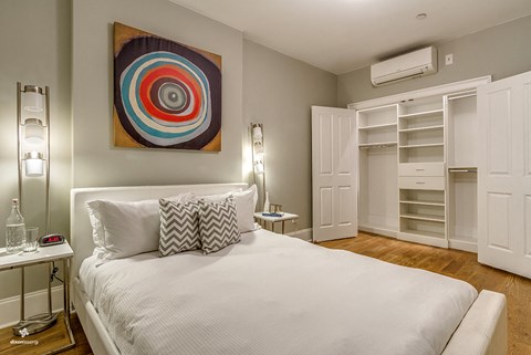 A bedroom with a large bed and a colorful artwork on the wall.