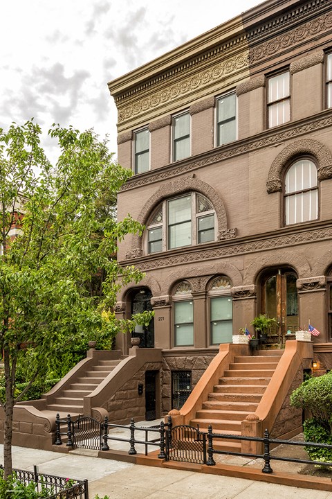 A brown building with a black fence in front.