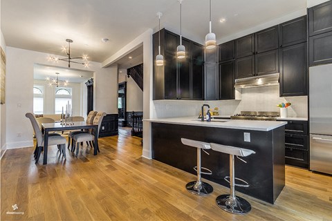 A modern kitchen with black cabinets and a wooden floor.