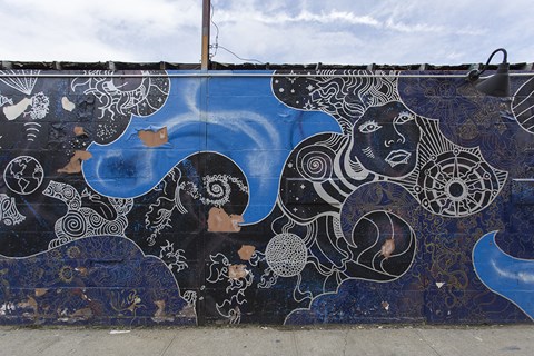 A wall with a blue and black mural of a face and swirls.
