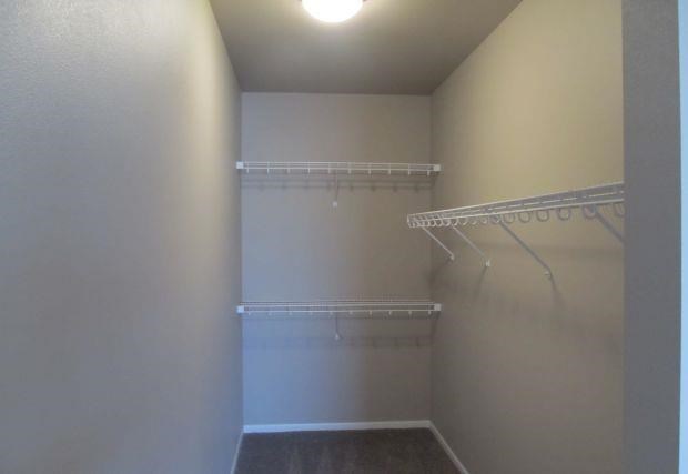 a white closet with white shelves and a light in it