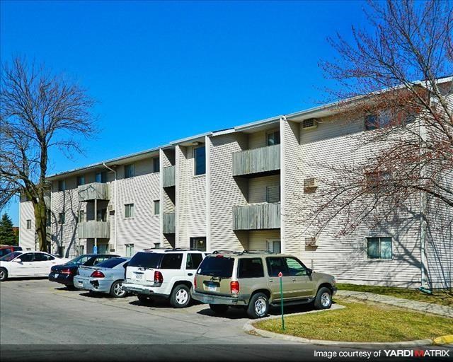 an apartment building with cars parked in a parking lot