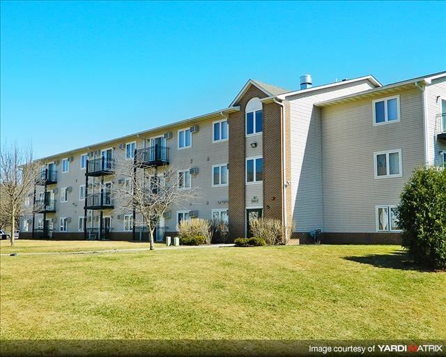 a large apartment building with a green lawn