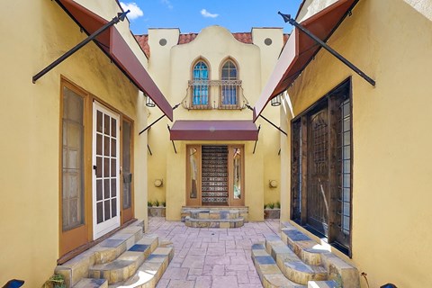 A yellow building with a red awning and a black door.