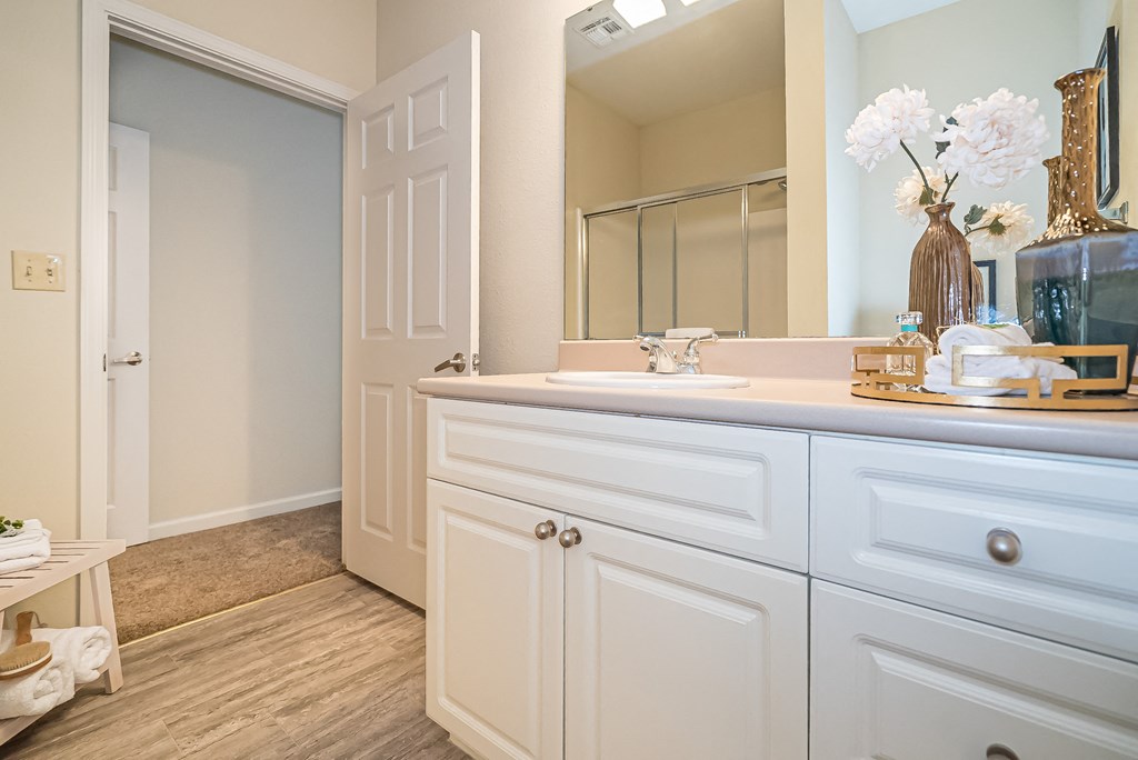 a bathroom with white cabinets and a sink and a mirror