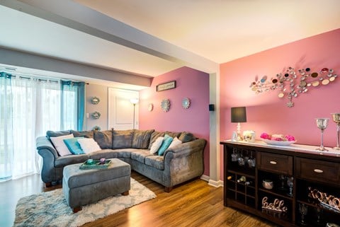 a living room with pink walls and a gray couch