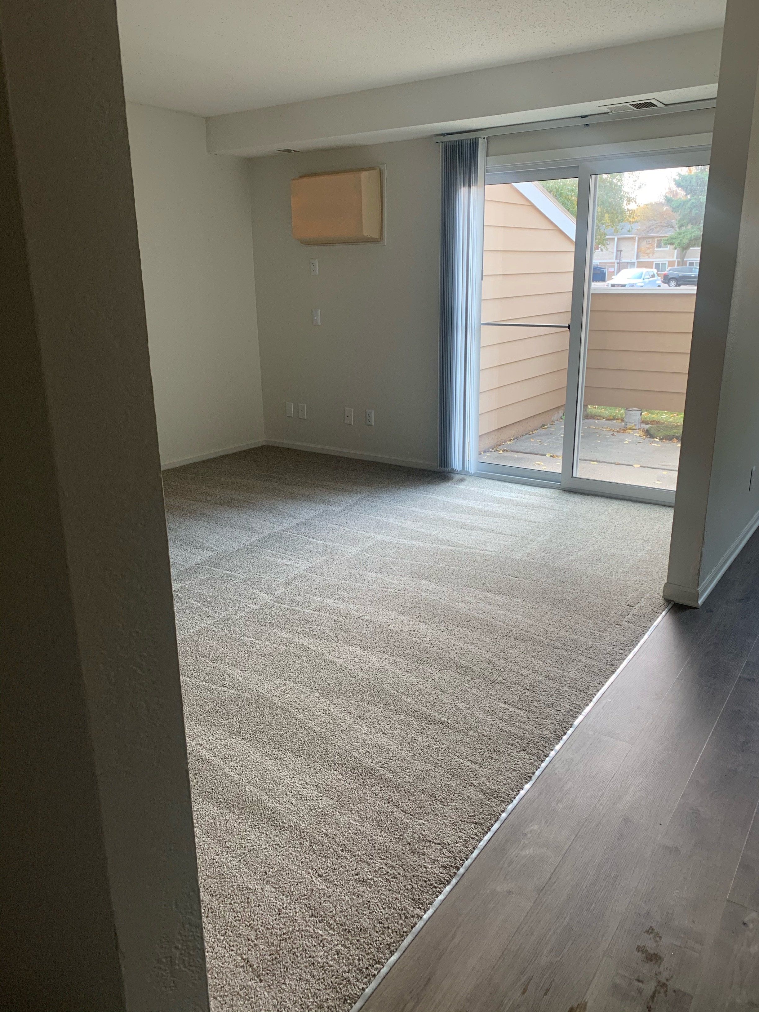 a living room with a carpet and a sliding glass door