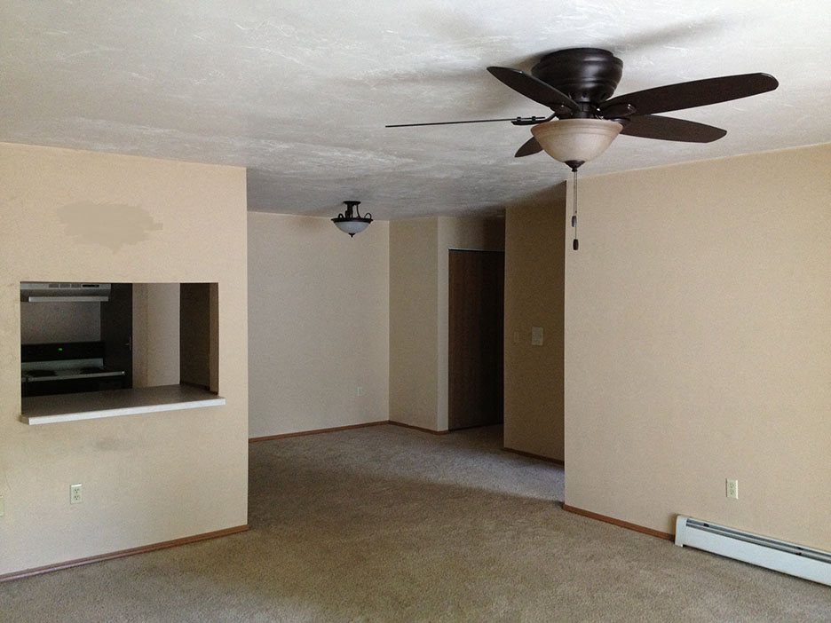 an empty living room with a ceiling fan