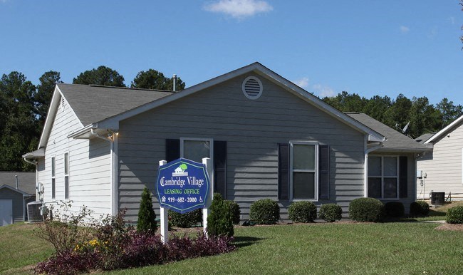 a gray house with a blue sign in front of it