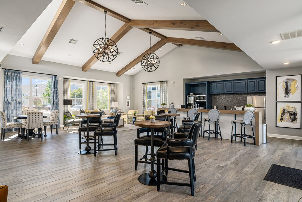 a large living room with tables and chairs and a kitchen