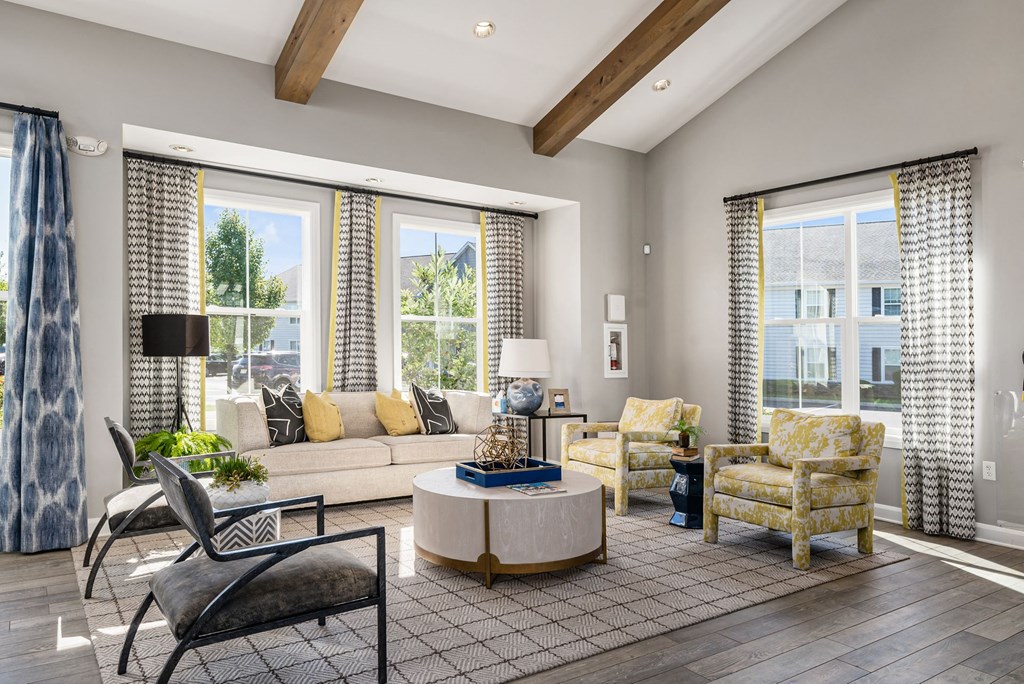 a living room with a couch and chairs and windows