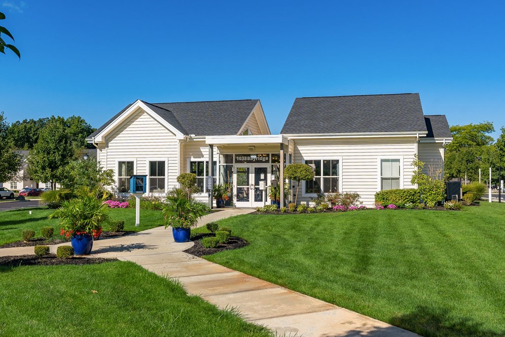 a white house with a lawn and a sidewalk in front of it