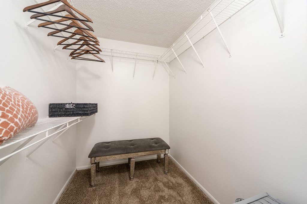 a walk in closet with a bench and a shelf