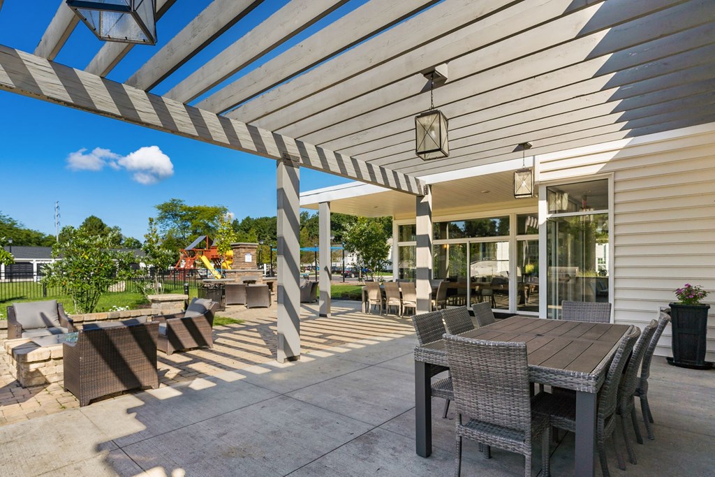 a covered patio with tables and chairs and a building in the background