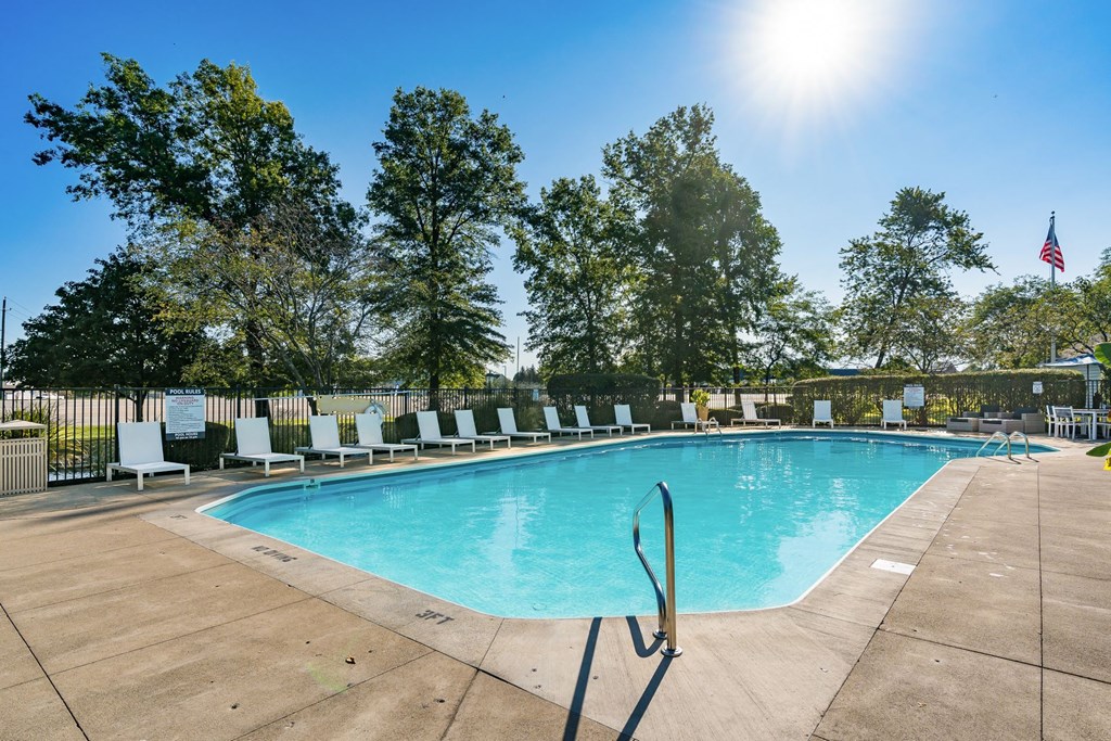 our resort style swimming pool is surrounded by lounge chairs and trees