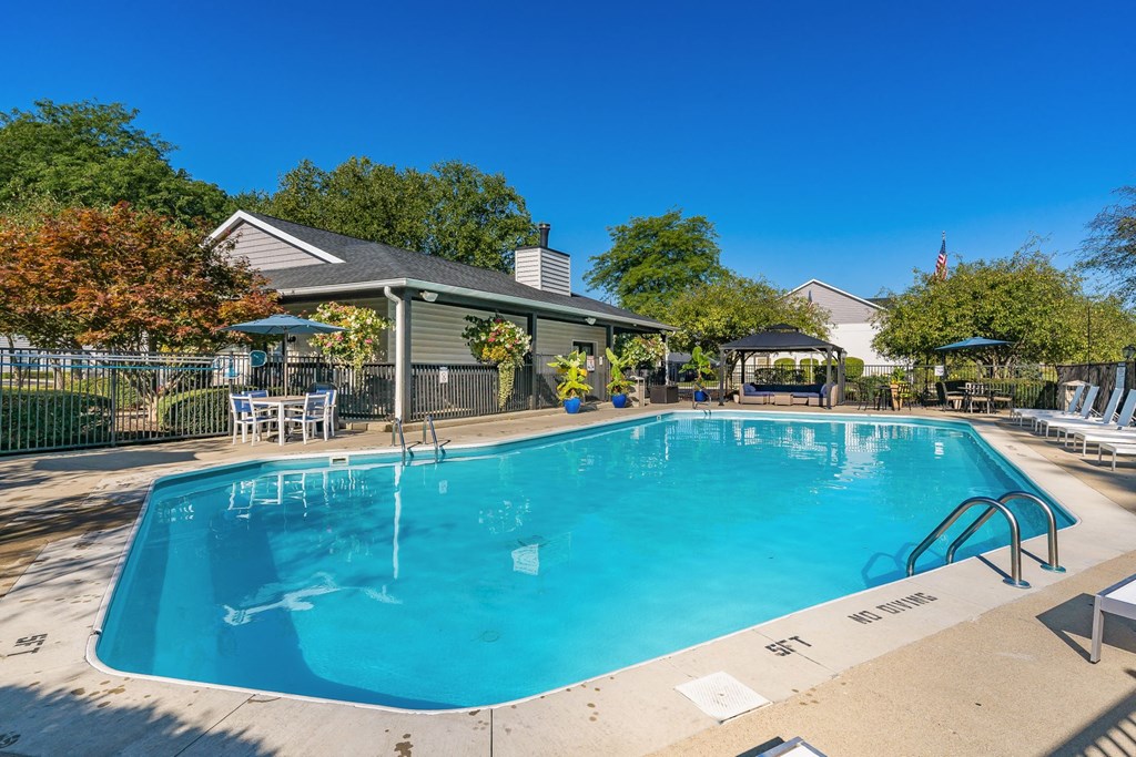 A large outdoor swimming pool with a pavilion and lounge chairs.