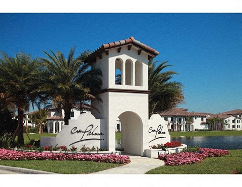 a building with a clock tower in front of a pond and palm trees