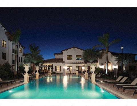 a large swimming pool at night in front of a hotel