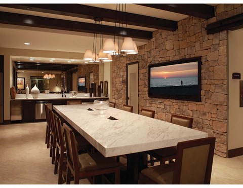 a dining room with a marble table and a tv on the wall