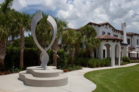 a sculpture in front of a house with palm trees