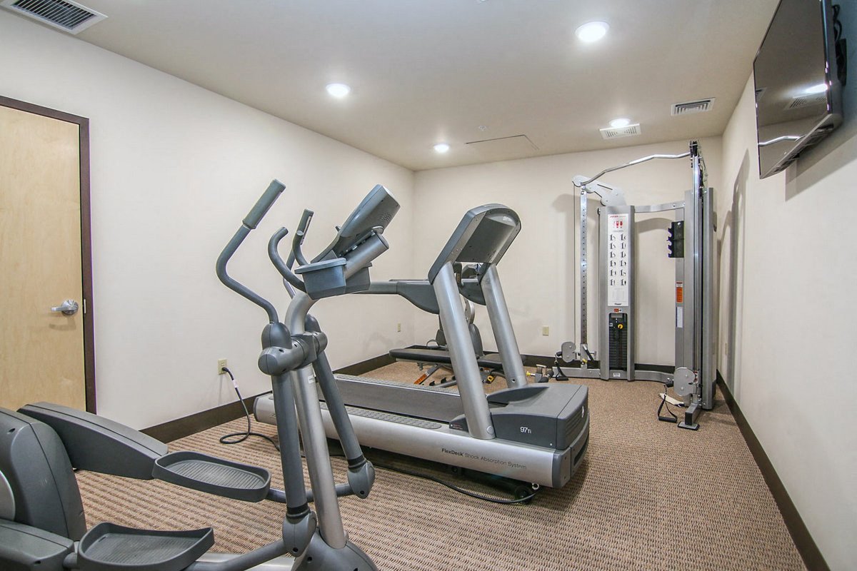 a gym with a treadmill and weights in the corner of a room
