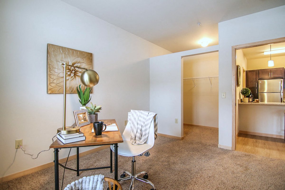 a living room with a desk and a door to a bathroom