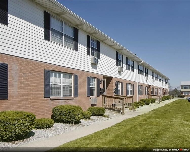 an apartment building with a sidewalk and grass