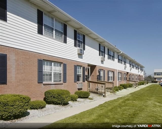 an apartment building with a sidewalk and grass