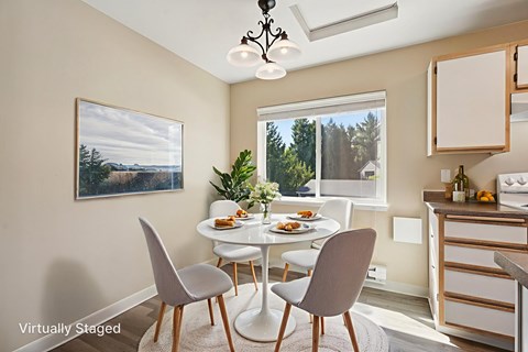A dining room with a table set for two and a painting of a landscape on the wall.