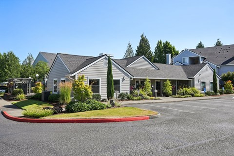 A parking lot in front of a building with grey roofs.