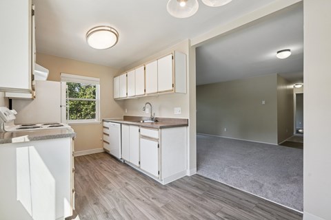 A kitchen with white cabinets and a grey floor.
