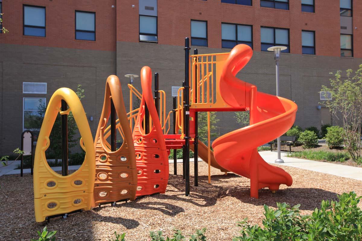 a playground with a slide and other equipment in front of a building