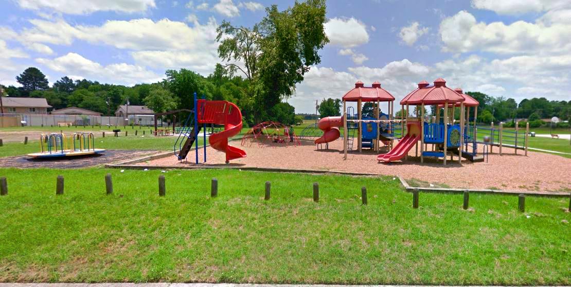 A playground with a red slide and a blue and yellow play structure.