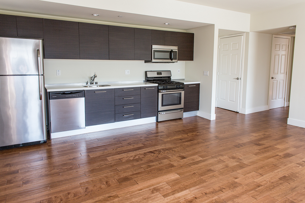 an empty kitchen with wooden floors and stainless steel appliances