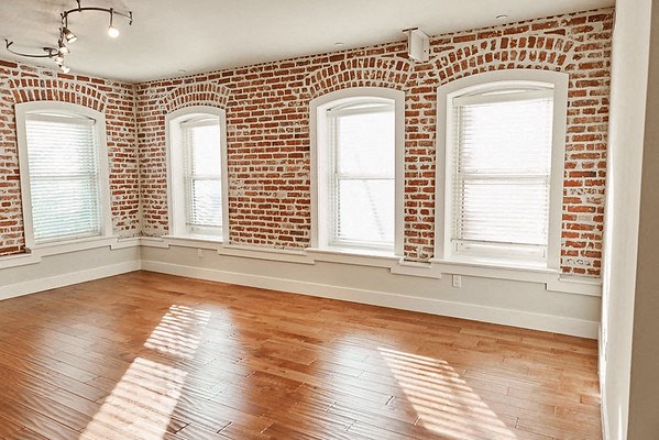 an empty room with a brick wall and a wood floor