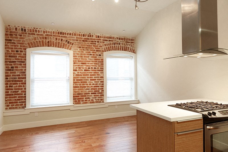 an empty kitchen with a stove and a brick wall