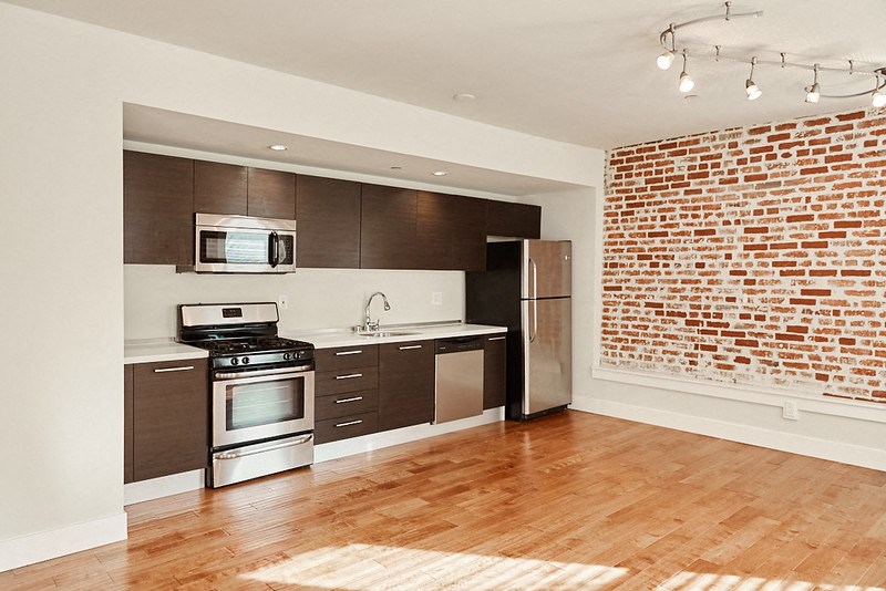 a kitchen with a brick wall and wooden floors
