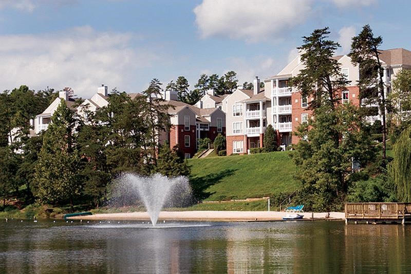 a fountain on a lake in front of an apartment building