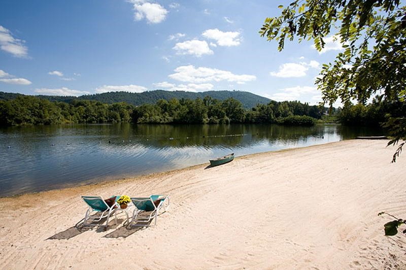 a beach with two chairs and a boat on the water