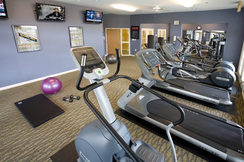 a gym with various exercise machines and a purple ball