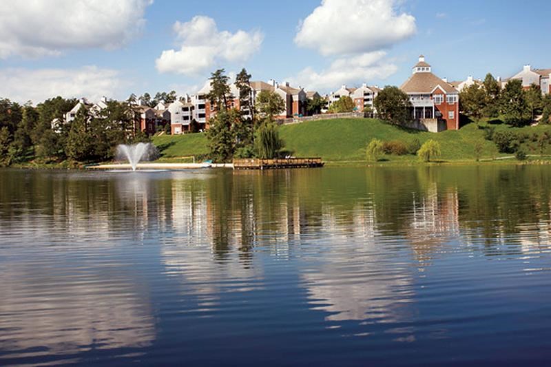 a lake with a fountain  and buildings on a hill