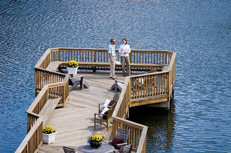 two people standing on a dock on the water