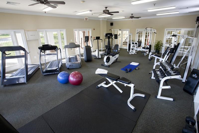 a gym with cardio equipment and exercise balls on the floor