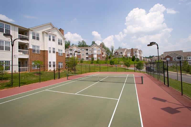 a tennis court with apartments in the background